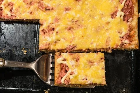 Rectangular slice of pizza on the shoulder, cooked at home, dish on a black t Stockfoto's