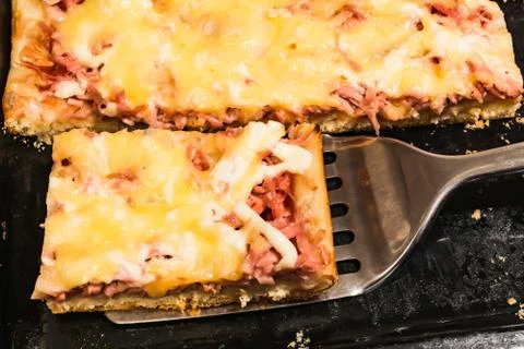 Rectangular slice of pizza on the shoulder, cooked at home, dish on a black t 写真素材