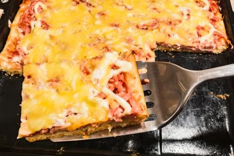 Rectangular slice of pizza on the shoulder, cooked at home, dish on a black t Stockfoto's