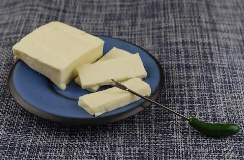 Rectangular slice of processed cheese in a blue saucer on a denim background. Foto stock