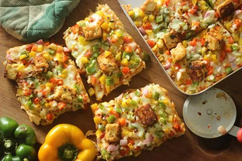 Rectangular slices of home baked pizza loaded with paneer, mozzarella cheese, Foto stock