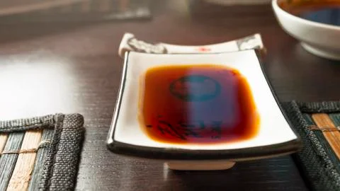 Rectangular Soy Sauce Dipping Dish on a Dark Table with Bamboo Dining Mats. C Stock Photos