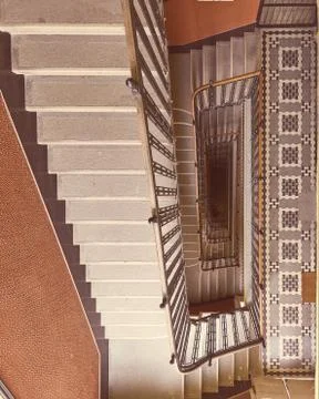 Rectangular spiral staircase with red wall black railings and square patterns Stock Photos