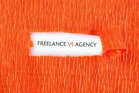 A rectangular tear in textured orange paper uncovers the phrase FREELANCE VS  Stock Photos