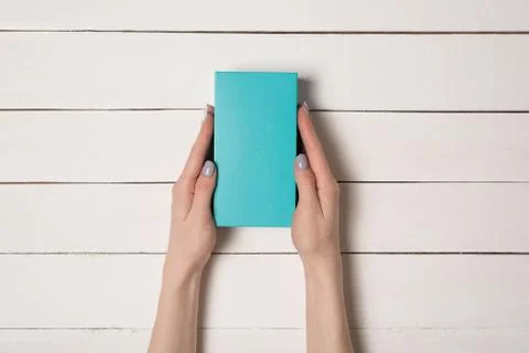Rectangular turquoise box in female hands. Top view. White table on the backg 写真素材