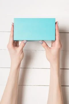 Rectangular turquoise box in female hands. Top view. White table on the backg 스톡 사진