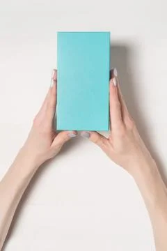 Rectangular turquoise box in female hands. Top view. White table on the backg Foto stock