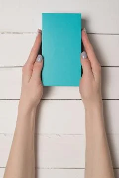 Rectangular turquoise box in female hands. Top view. White table on the backg 写真素材