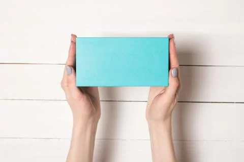 Rectangular turquoise box in female hands. Top view. White table on the backg Foto stock