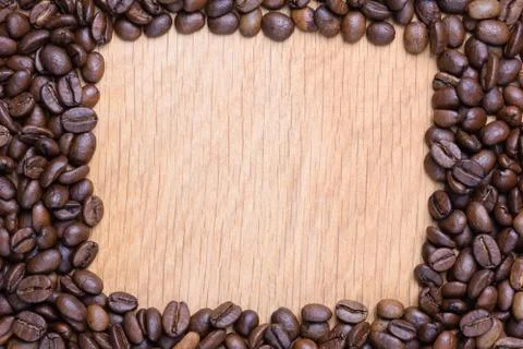 A rectangular void is laid out on a wooden surface made of coffee beans. Stock Photos