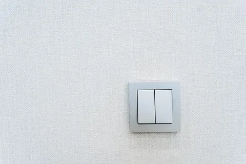 Rectangular white light switch on a white wall with symmetrical placement Foto stock
