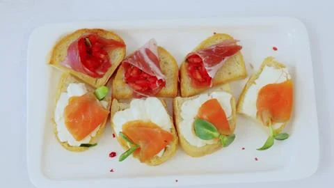 Rectangular white plate displaying open faced sandwiches topped with smoked Stock Photos