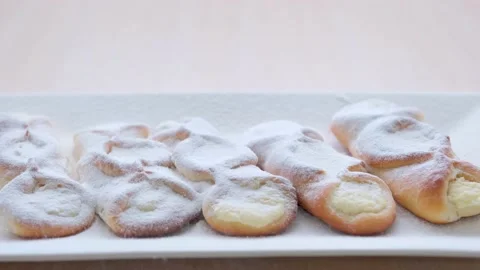 On rectangular white porcelain plate slowly sprinkle cottage cheese pies with Vídeos de archivo 233690442