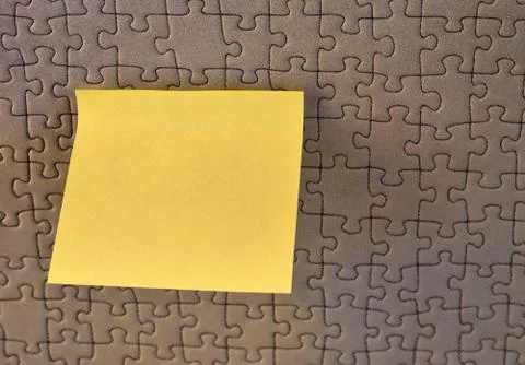 Rectangular yellow note paper attached to puzzle shape background. A piece of Stock Photos
