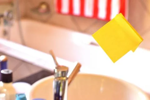 Rectangular yellow note paper attached on toilet mirror. Piece of square sheet Stock Photos