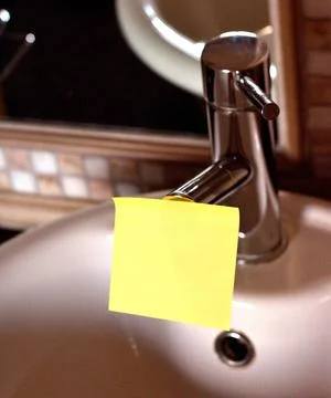 Rectangular yellow note paper attached on toilet sink faucet. Piece of squ... 写真素材