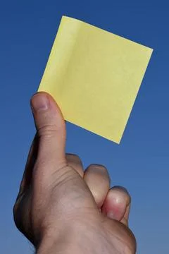 Rectangular yellow note paper held by one hand raising up to the sky. A pe... 스톡 사진