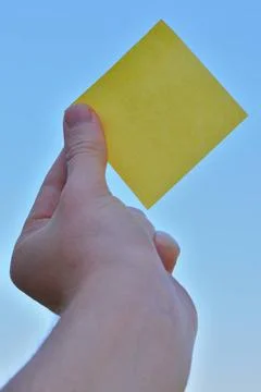 Rectangular yellow note paper held by one hand raising up to the sky. A pe... 스톡 사진