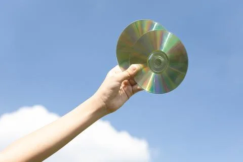 Recyclable CD disk held in hand up on sky-like isolated background. Gyre Stock Photos