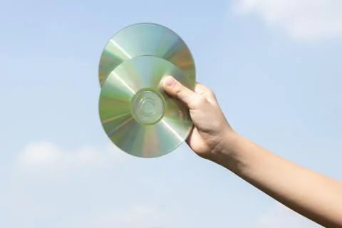 Recyclable CD disk held in hand up on sky-like isolated background. Gyre Stock Photos