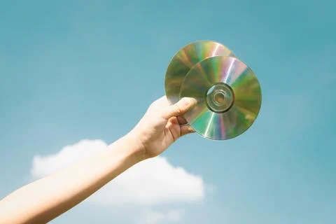 Recyclable CD disk held in hand up on sky-like isolated background. Gyre Stock Photos