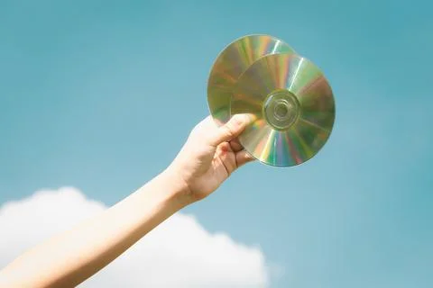 Recyclable CD disk held in hand up on sky-like isolated background. Gyre Stock Photos