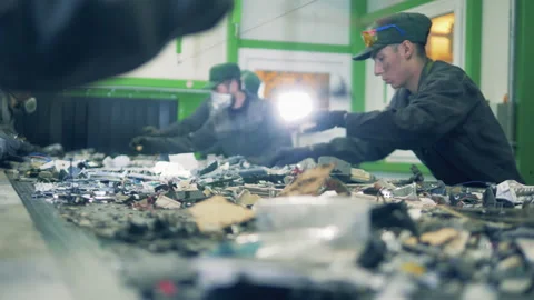 Recycling center workers sort garbage on a conveyor. Video stock 135661421