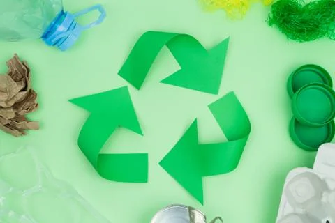 Recycling logo on green background with objects to recycle. Stock Photos