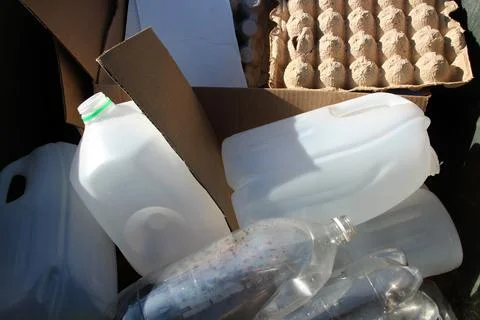 Recycling materials including plastic bottles, cartons, and cardboard in a bi Stock Photos