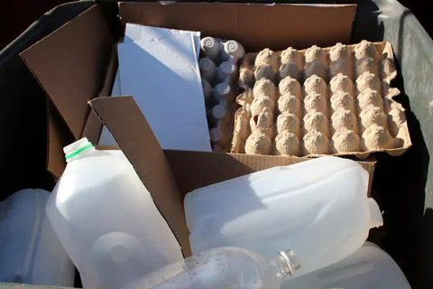 Recycling materials including plastic bottles, cartons, and cardboard in a bi Stock Photos