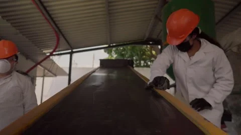 Recycling plant workers clean conveyor belt handling HDPE plastic for Stock Footage 346643713