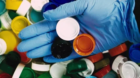 Recycling of plastic bottle caps. The hand drops the caps Stock Footage 219378853