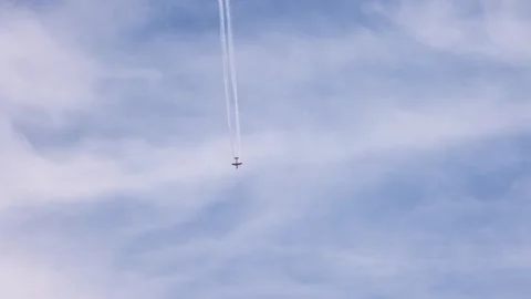 Red aerobatic plane flying high in blue sky with white smoke trails followi.. Stock Footage 332833103