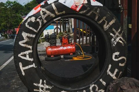 Red air compressor seen through a used tire at a roadside shop Stock-Fotos