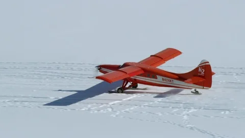 Red airplane taking off from ground covered in white snow, Tordrillo Mountain Видео 129128724