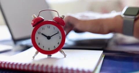 Red alarm clock and hands typing on computer keyboard Stock Footage 209461423