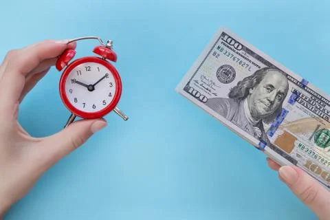 Red alarm clock and a stack of money in hands on a blue background Stock Photos