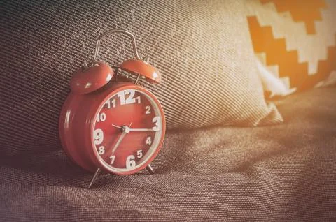 Red alarm clock on bed Stock Photos