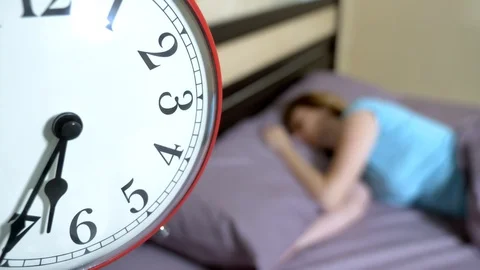 Red alarm clock close-up, on a blurred background, the girl is angry that the Stock Footage 111494711