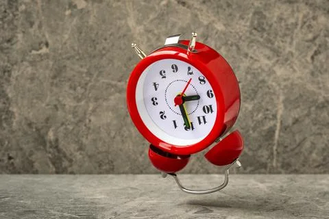 Red alarm clock falling on the stone background Stock Photos