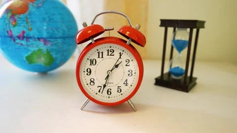 Red alarm clock with globe and hourglass on a desk Stock Footage 316745272