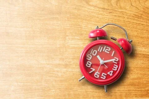 Red alarm clock on old brown wooden plank background. Foto stock