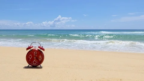 Red alarm clock placed on the beach, the sea on a beautiful sky day. 库存影片 95781215
