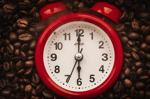 Red Alarm Clock Placed Centrally on Roasted Coffee Beans Foto stock