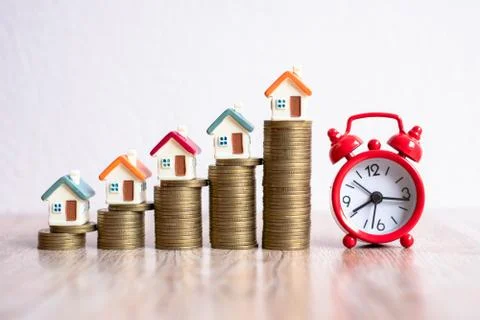 A red alarm clock placed on the table. Stair medals with houses placed on top Foto stock