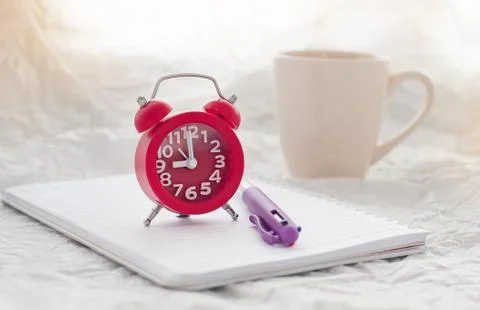 Red alarm clock put on blurred book,nine o'clock,in morning time,blurry light Stock Photos