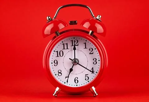 Red alarm clock on a red background. It's 7 o'clock on the clock. Morning. Foto stock