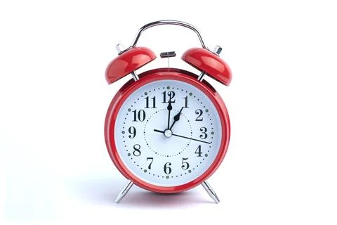 Red alarm clock set at five o'clock isolated on white background. Close-up .. Stock Photos