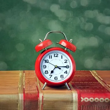 Red alarm clock on the table with a red tablecloth. Stock-Fotos