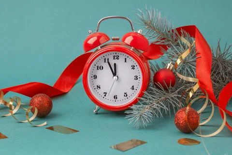 Red alarm clock on a table with red Christmas decor and fir branches Stock Photos